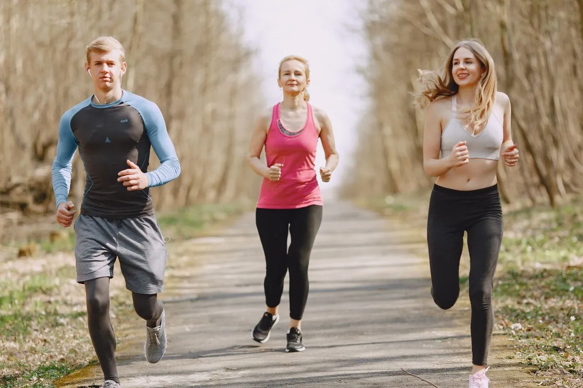 Drie beginnende hardlopers lopen samen over een parkpad
