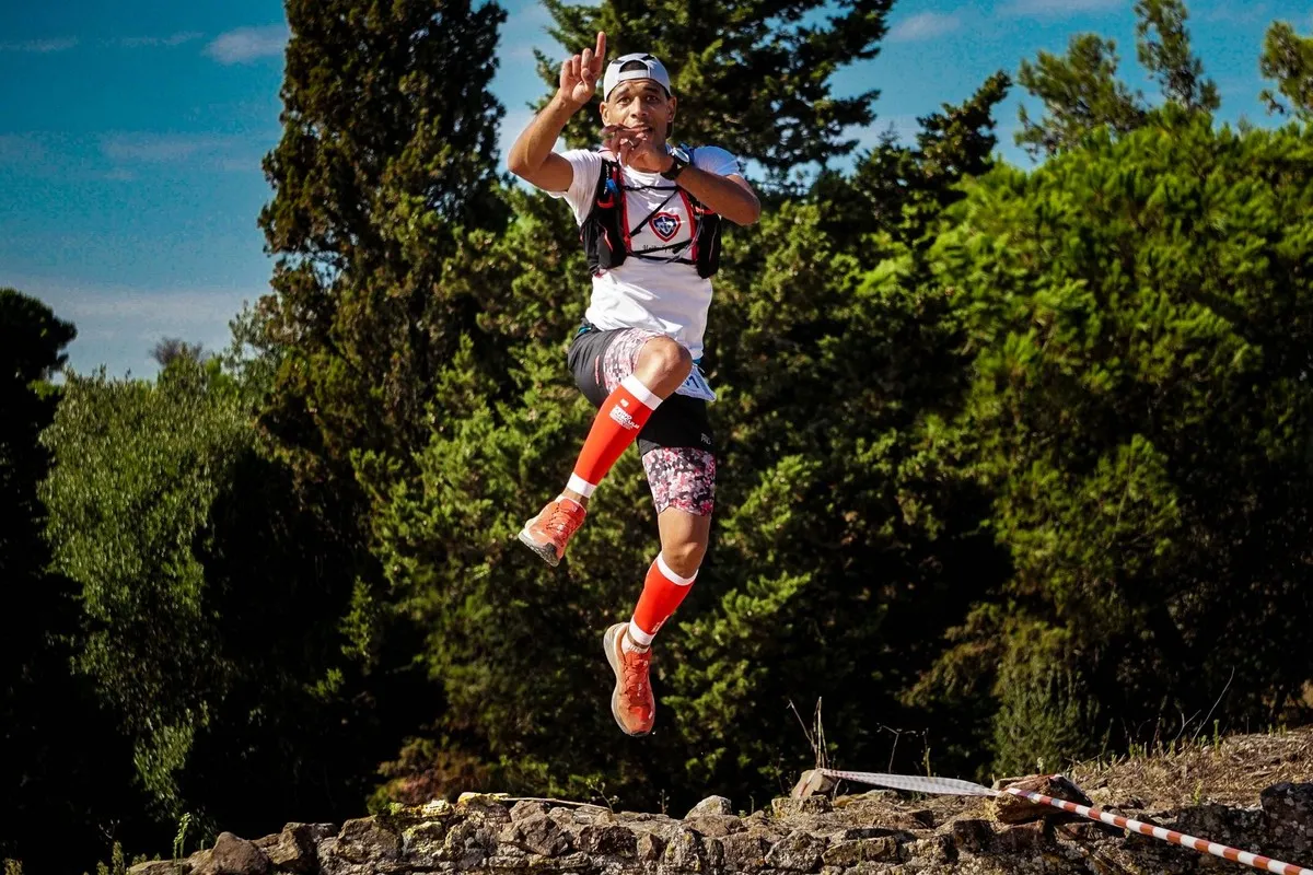 Trailloper met rode compressiekousen springt op een bospad