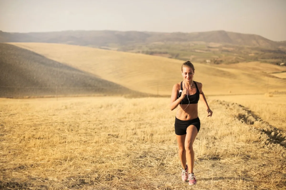 Hardloopster loopt op een warme dag door een droog veld en zweet flink