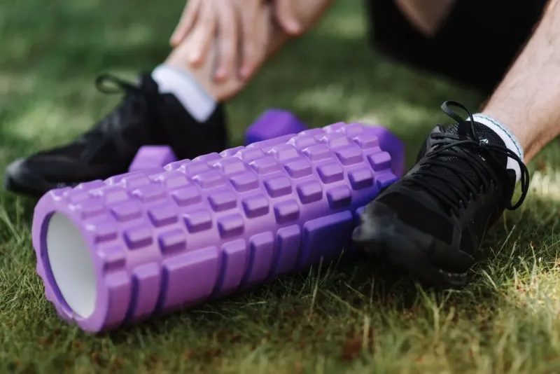 Paarse foam roller en hardloopschoenen op het gras na een training
