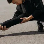 Hardloper met spierpijn rekt zijn bovenbeen voorzichtig op straat