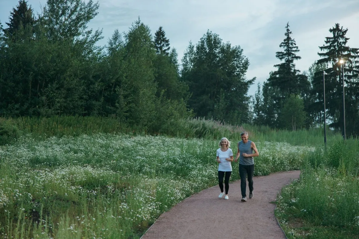 Ouder stel jogt rustig over een groen wandelpad