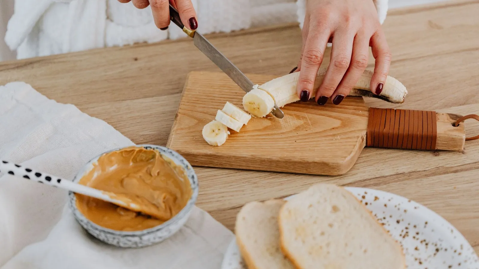 Wat eten voor hardlopen: banaan snijden op een plankje met pindakaas en brood